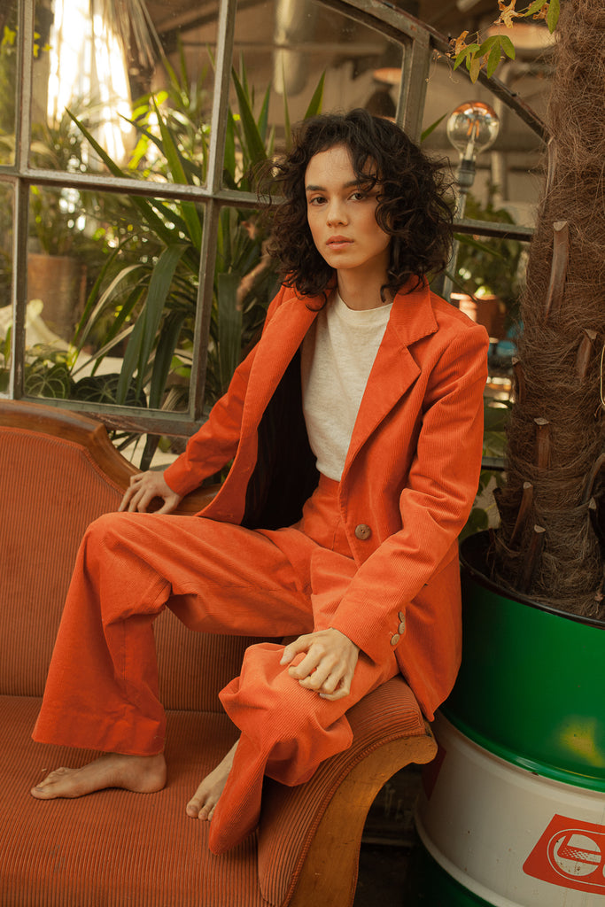 Crafted from 100% organic cotton corduroy, this fire coral-hued suit is complete with wood buttons and is hand-made in Zurich. Its versatile design makes it suitable for both business and casual events.